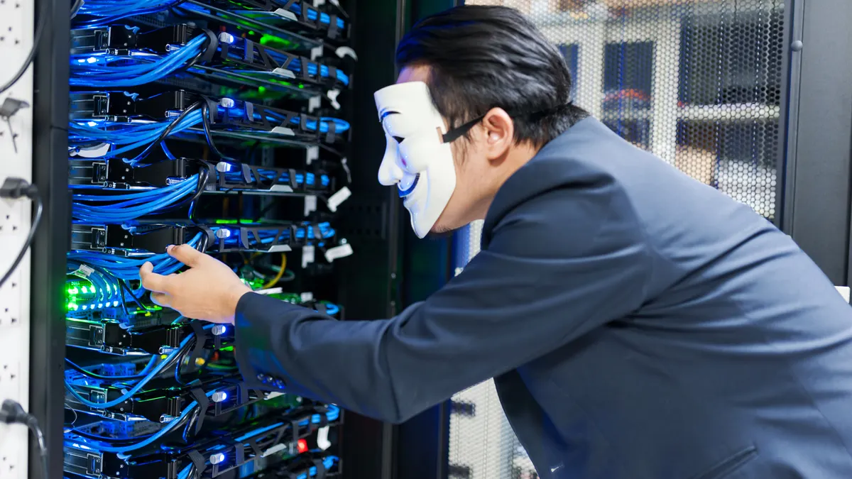 How to Track U.S. Cybersecurity Breaches in the Tech Sector masked person working by server racks