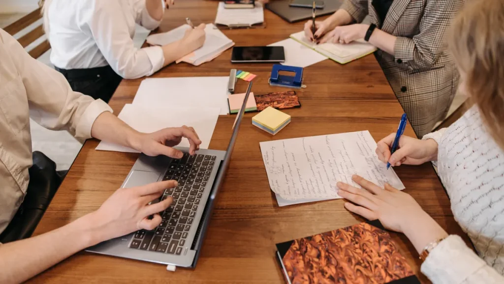 group meeting around a table with laptops and notes