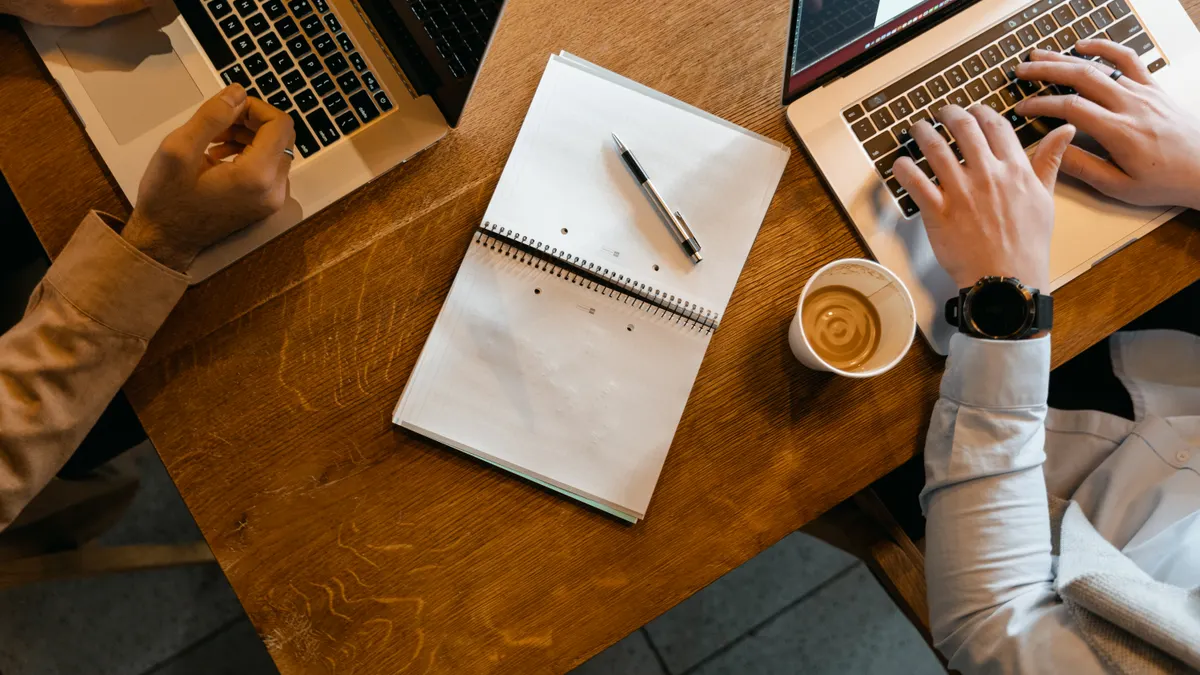How to Use AI for Meeting Notes and Action Items overhead view of people working with laptops and a notebook