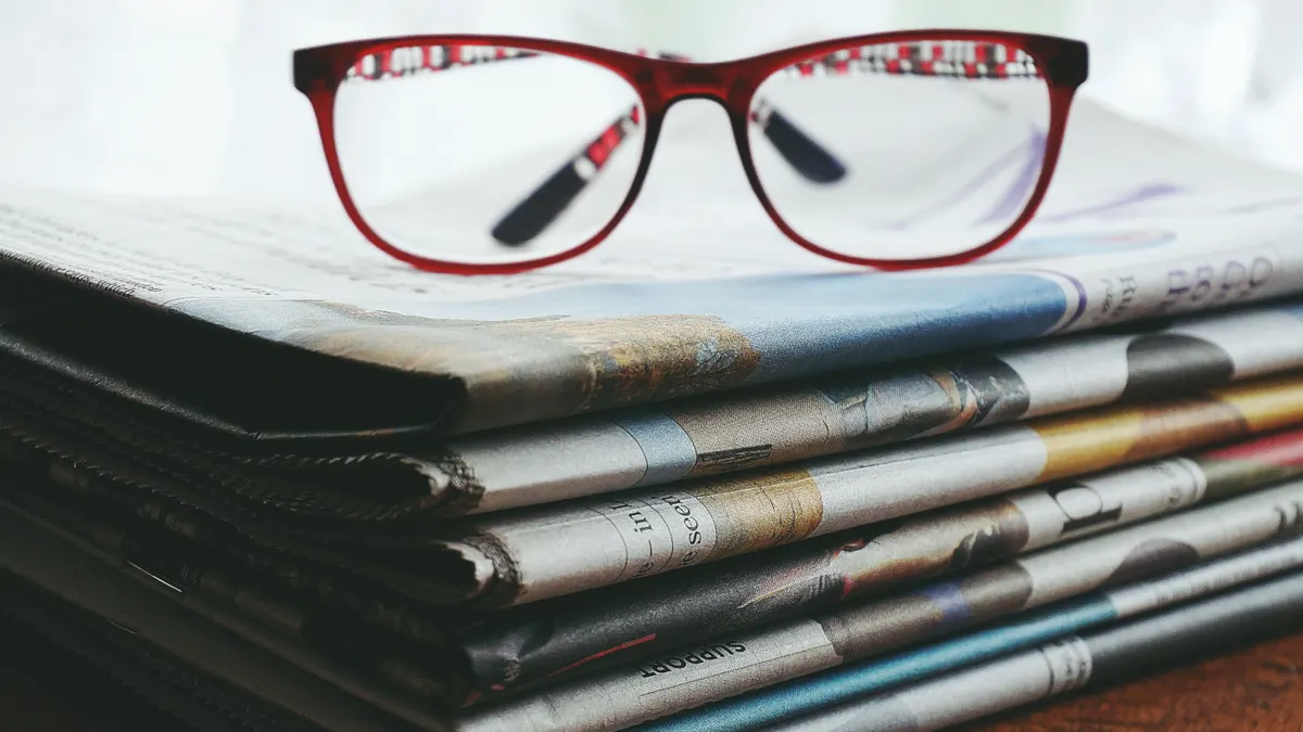 Red eyeglasses on a stack of newspapers